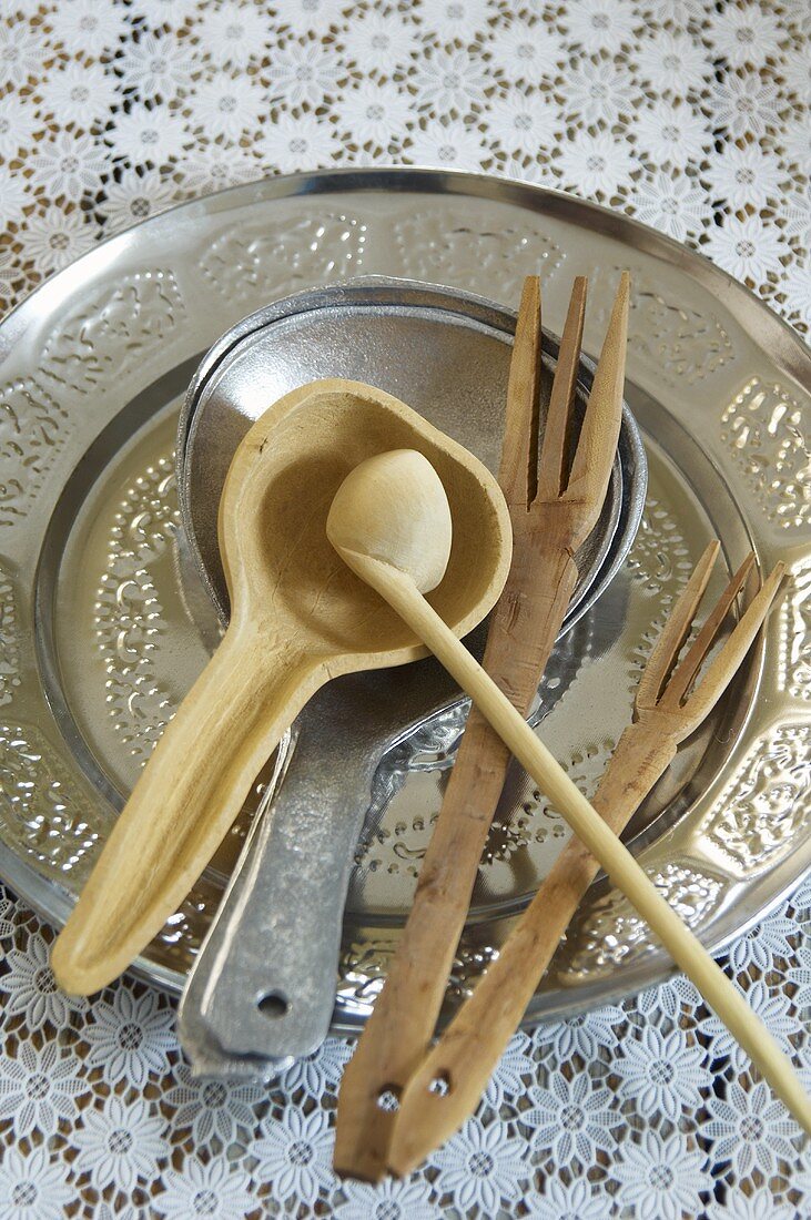 A silver dish with a draining spoon and wooden forks