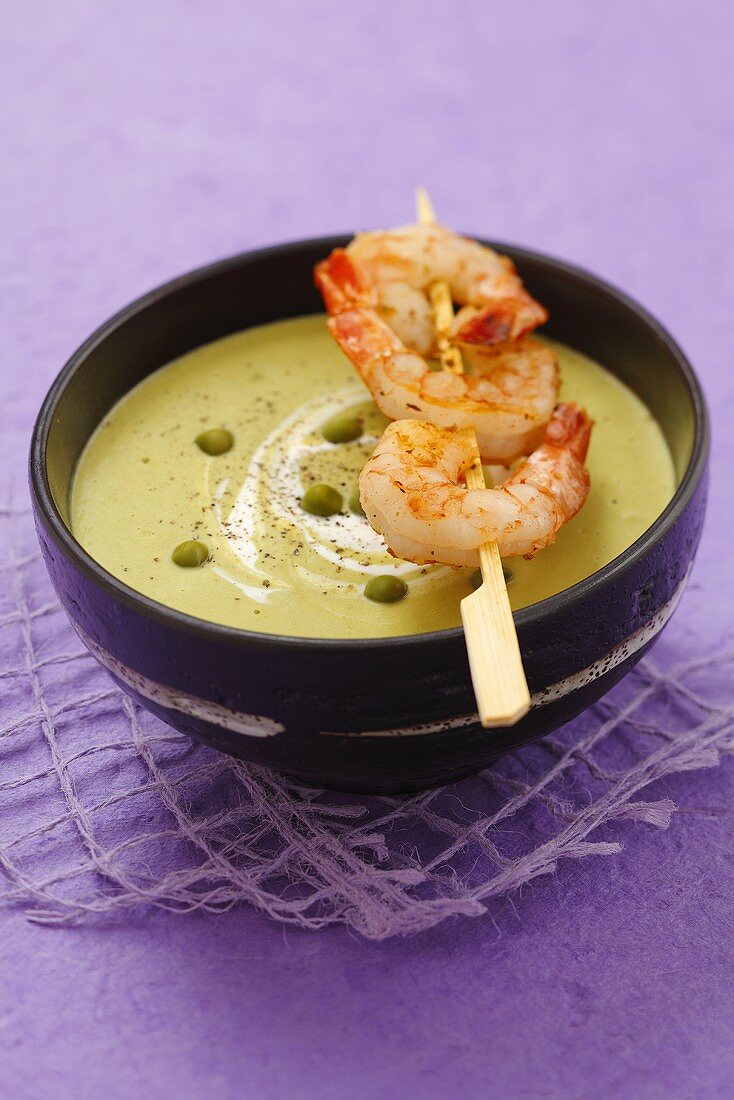 Pea cream soup with skewered prawns