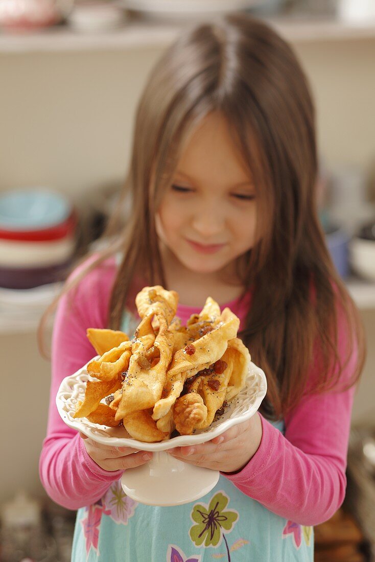 A girl holding a plate of faworki (deep-fried pastry, Poland)