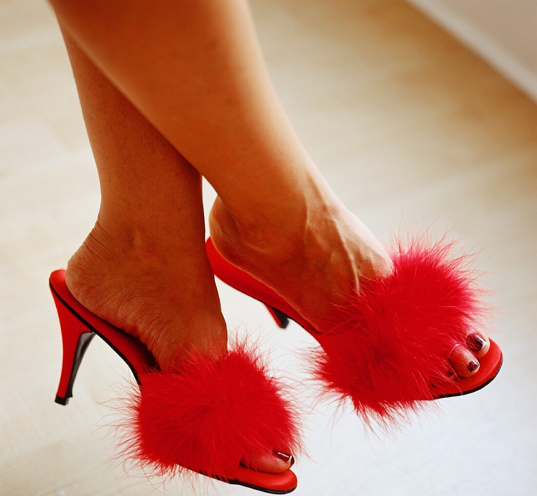 A woman wearing great, high-heeled shoes with fluffy pom-poms