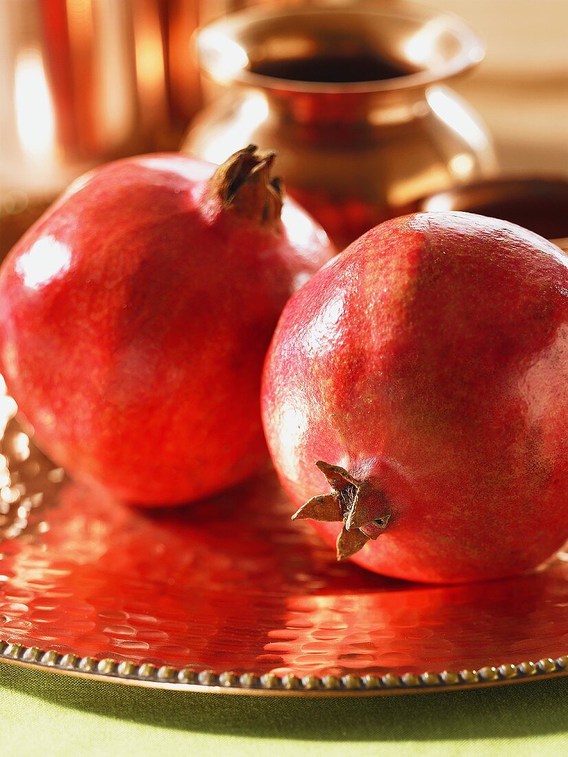 Two pomegranates on a copper tray