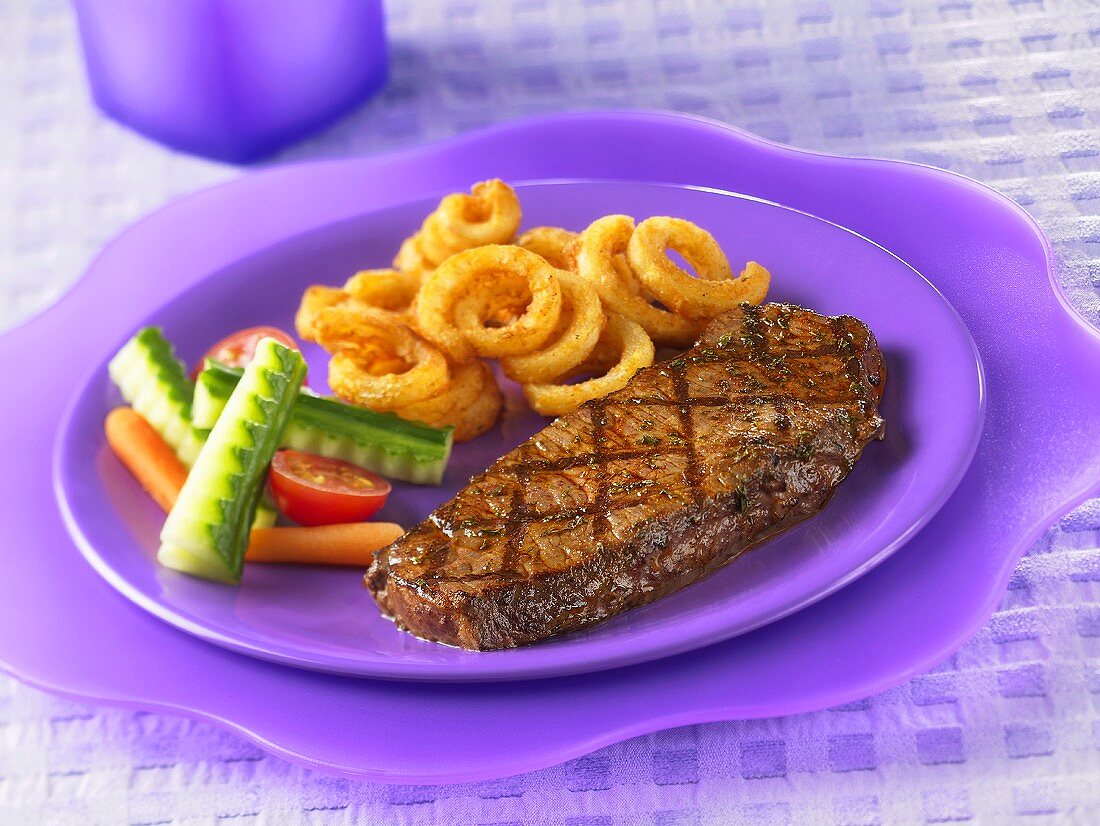 Beef steak with onion rings and vegetables