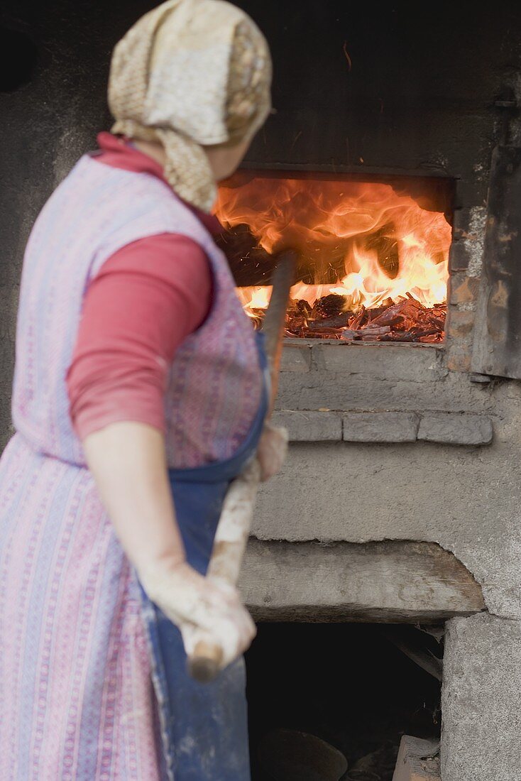 Bäuerin schiebt Brot in den Holzofen