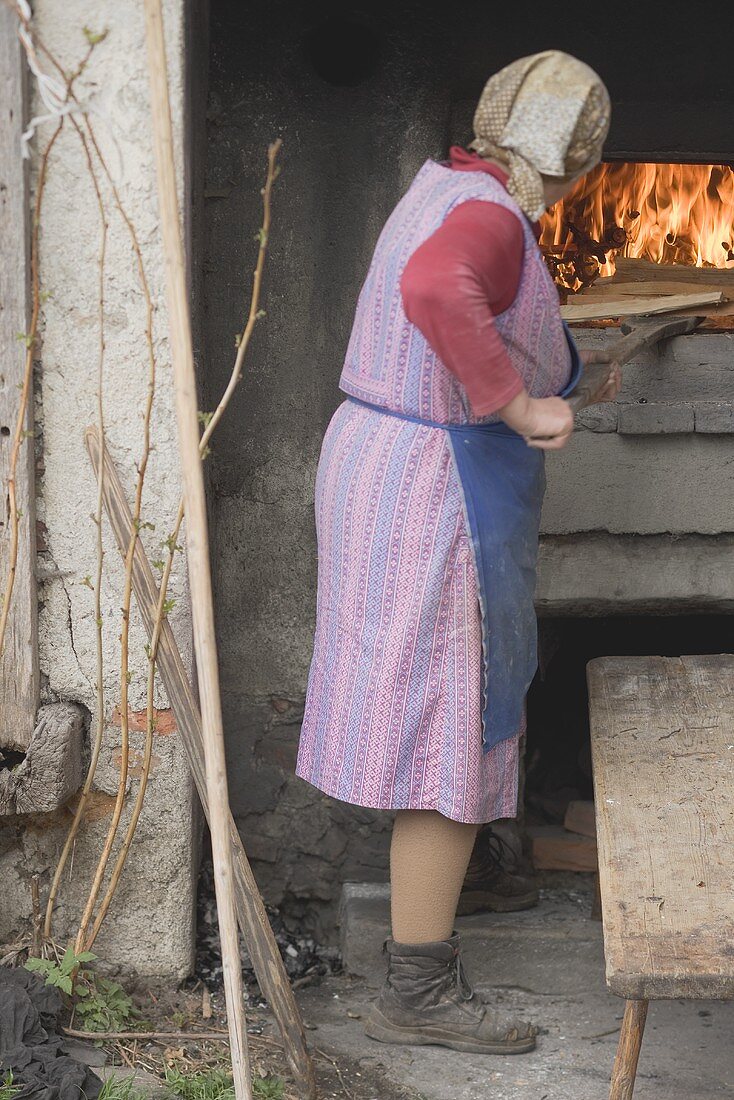 Countrywoman baking bread in stone oven