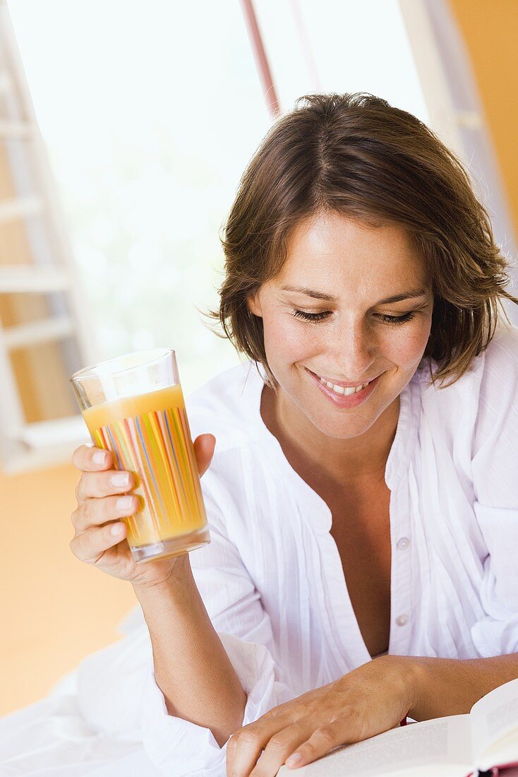 Young woman with orange juice and book