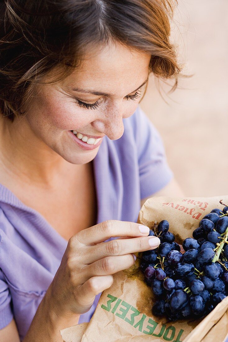 Frau isst blaue Weintrauben