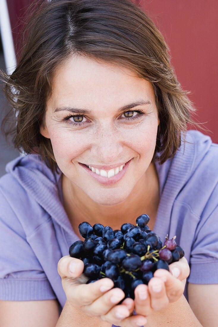 Junge Frau mit blauen Weintrauben