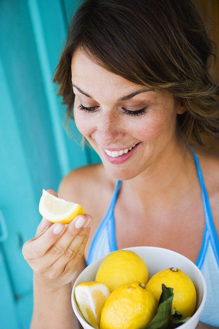 Frau hält eine Schale mit frischen Zitronen