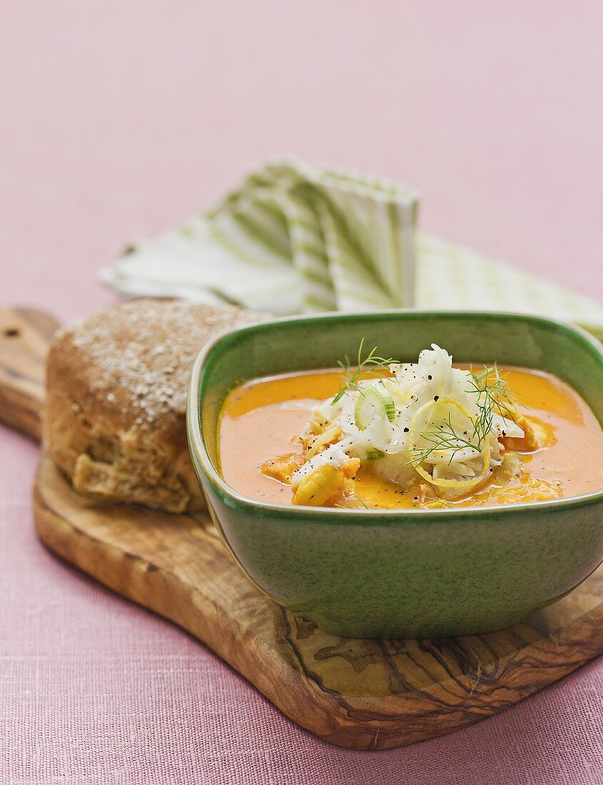 Fischsuppe mit Fenchel und Brot auf einem Holzbrett