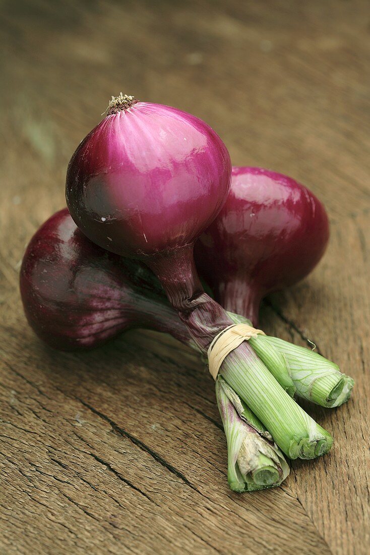 Three red onions on wooden background