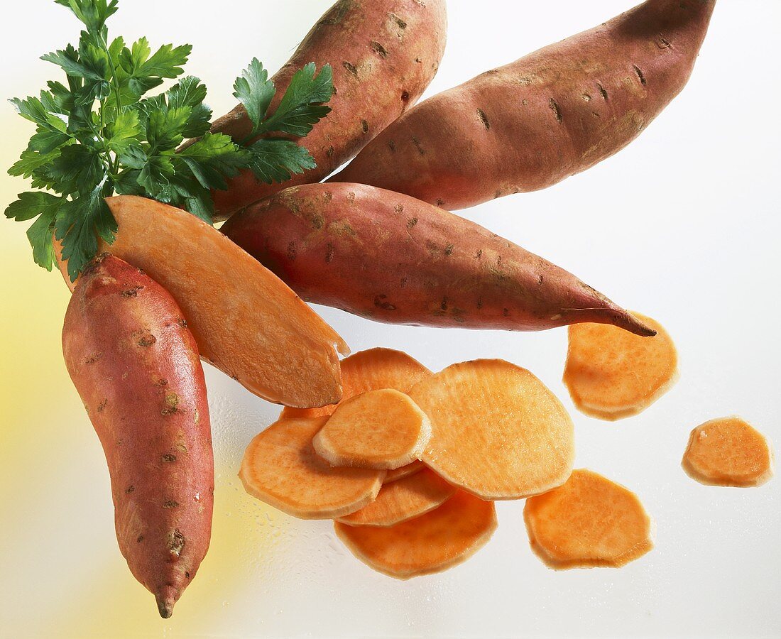 Whole and sliced sweet potatoes with parsley
