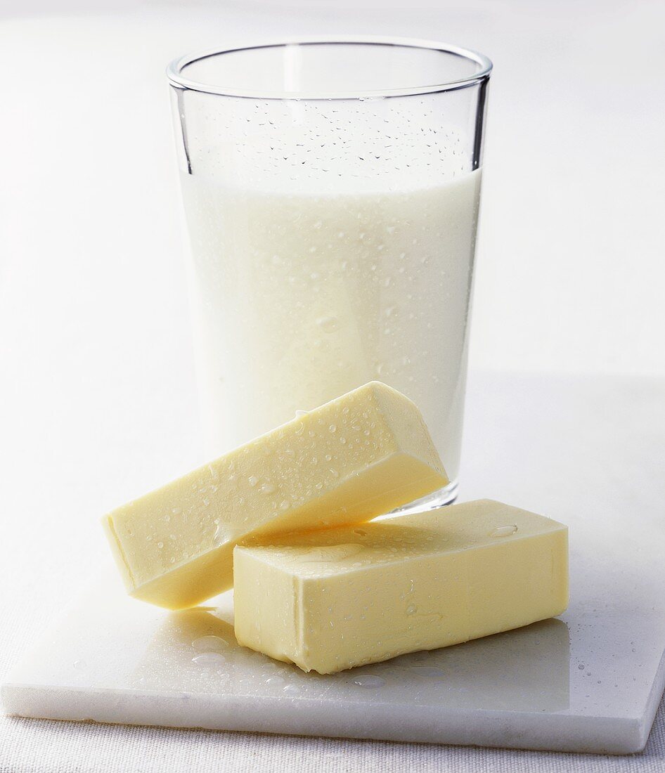 A glass of buttermilk with pieces of butter in front