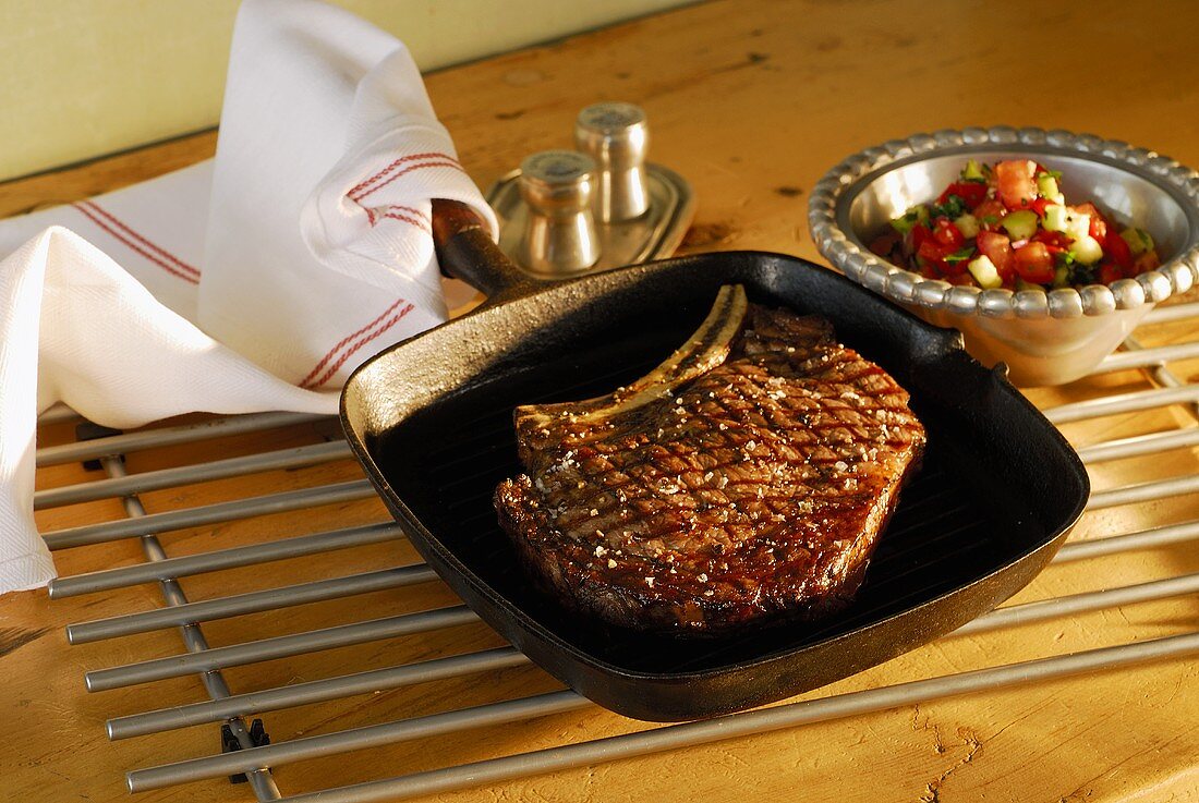 Beef steak in a grill pan with pepper and cucumber salad
