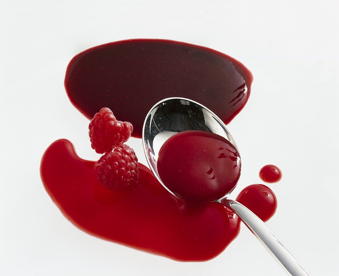 Raspbery sauce with a spoon and fresh raspberries