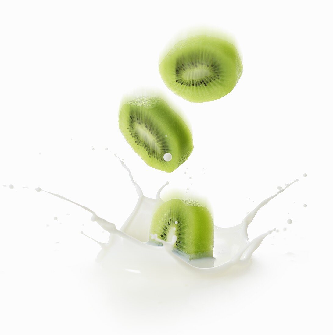 Slices of kiwi fruit falling into milk