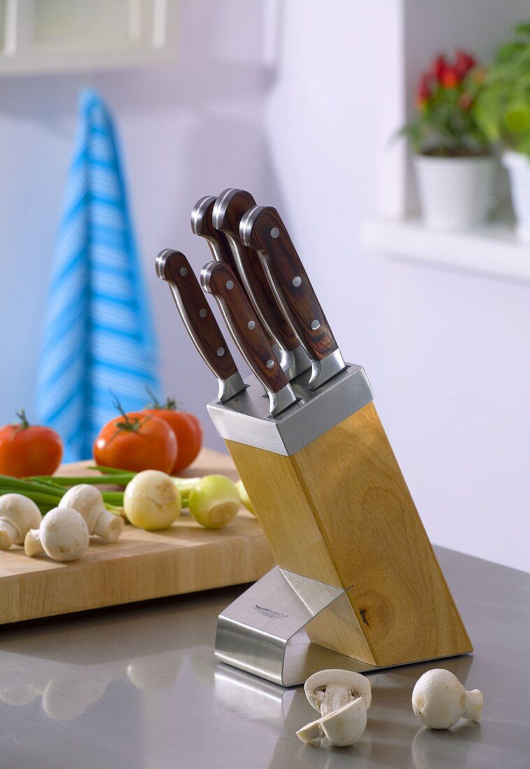 Knife in knife block, vegetables in background