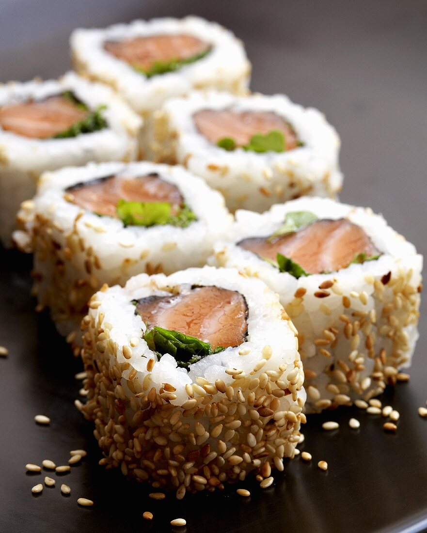 Six California rolls with salmon and sesame seeds