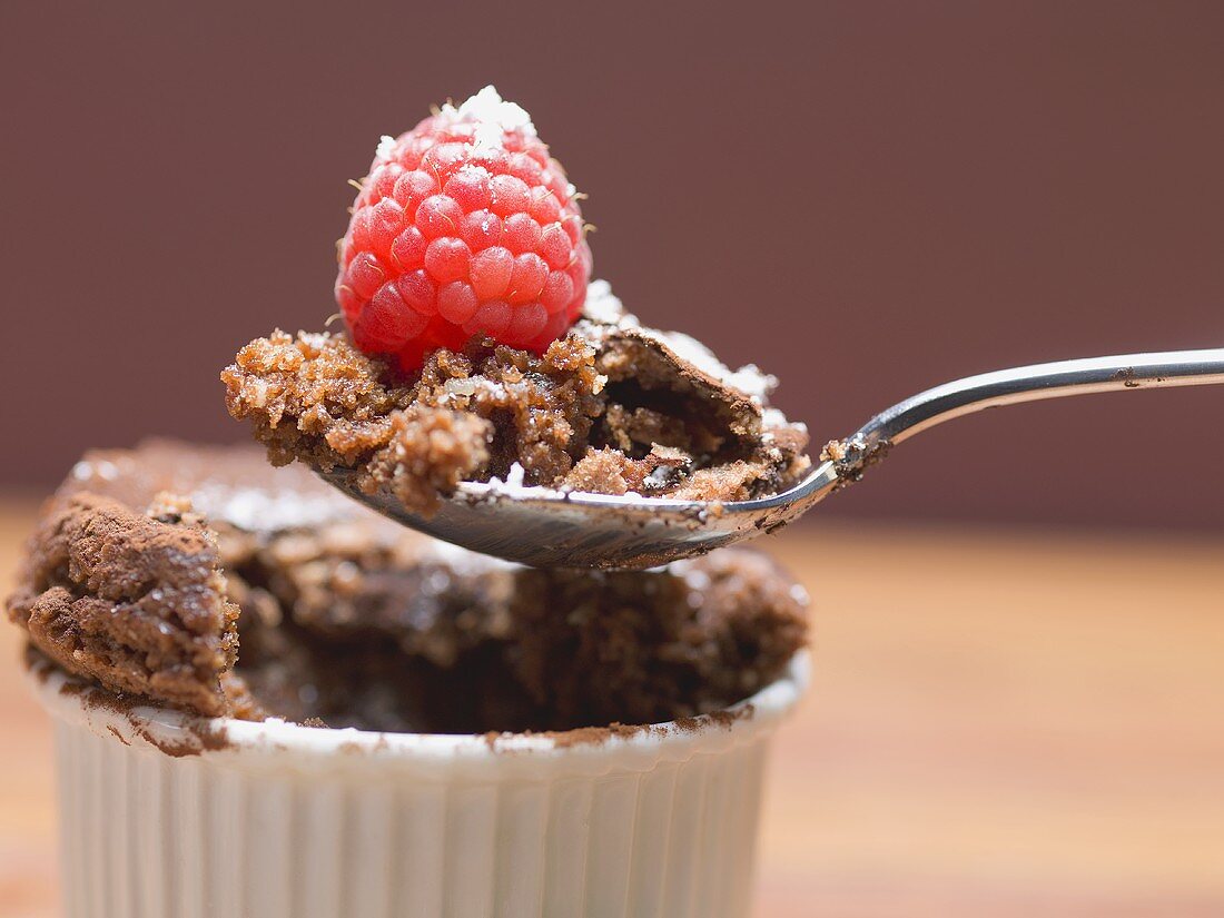 Schokoladensouffle in Backform und auf Löffel mit Himbeere