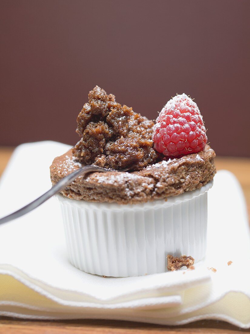Chocolate soufflé in ramekin & on spoon with raspberry