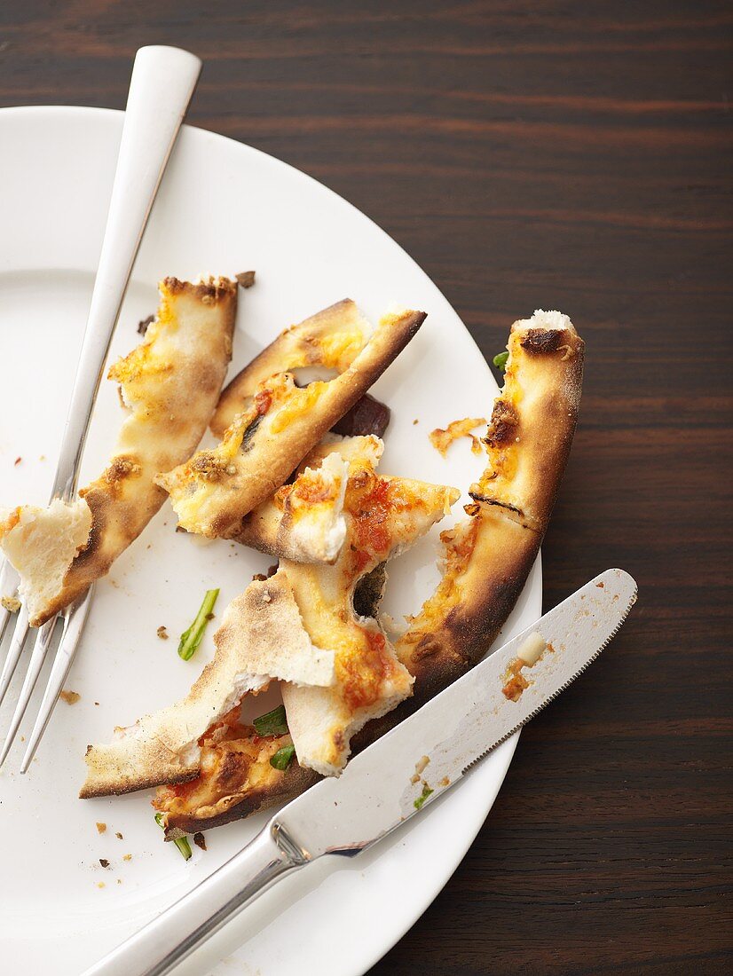 Remains of pizza on plate with knife and fork