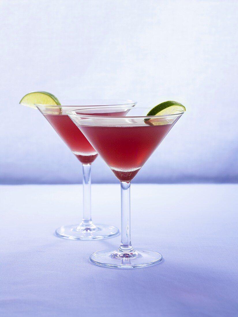 Two pomegranate cocktails with slices of lime