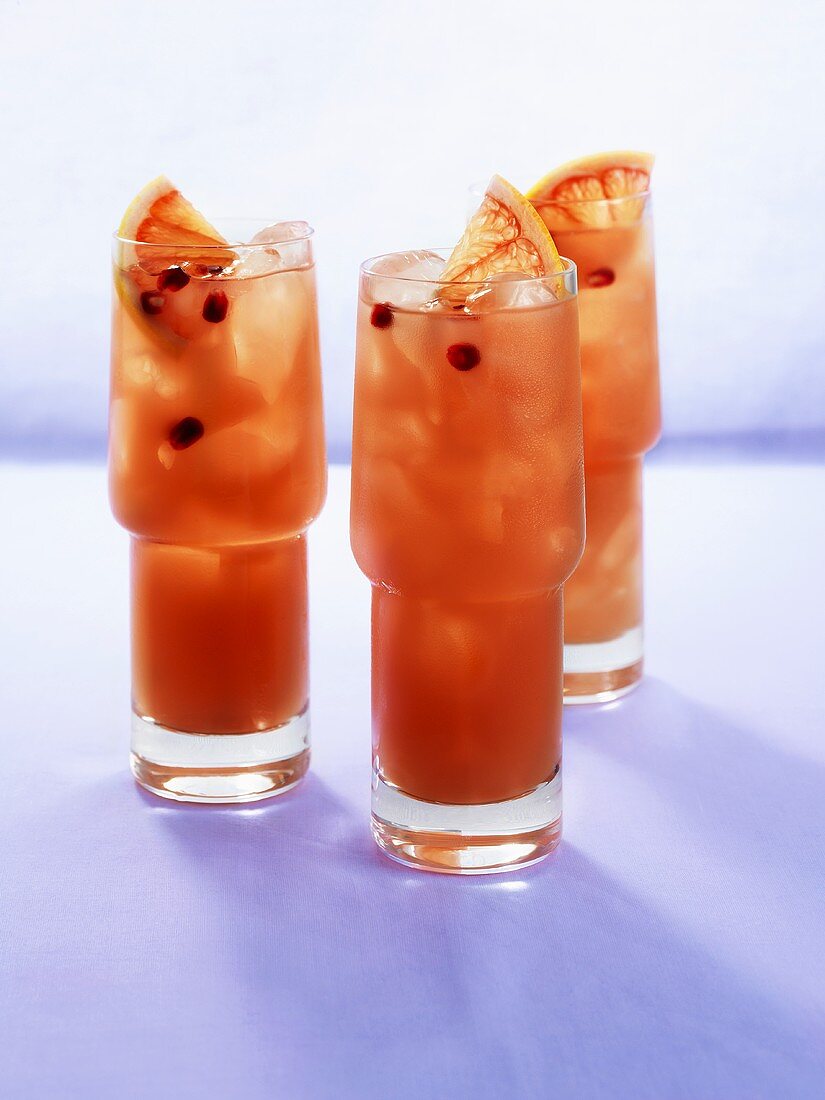 Three pomegranate drinks with slices of blood orange