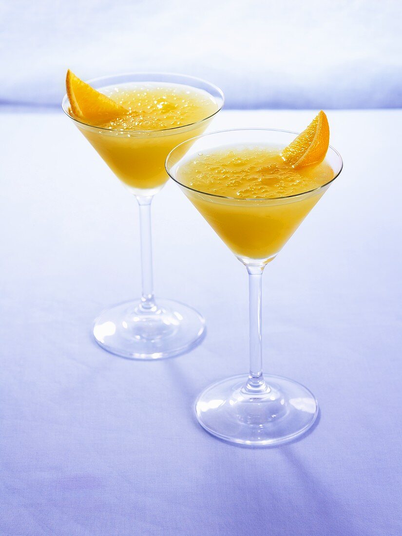 Two peach and orange cocktails in Martini glasses