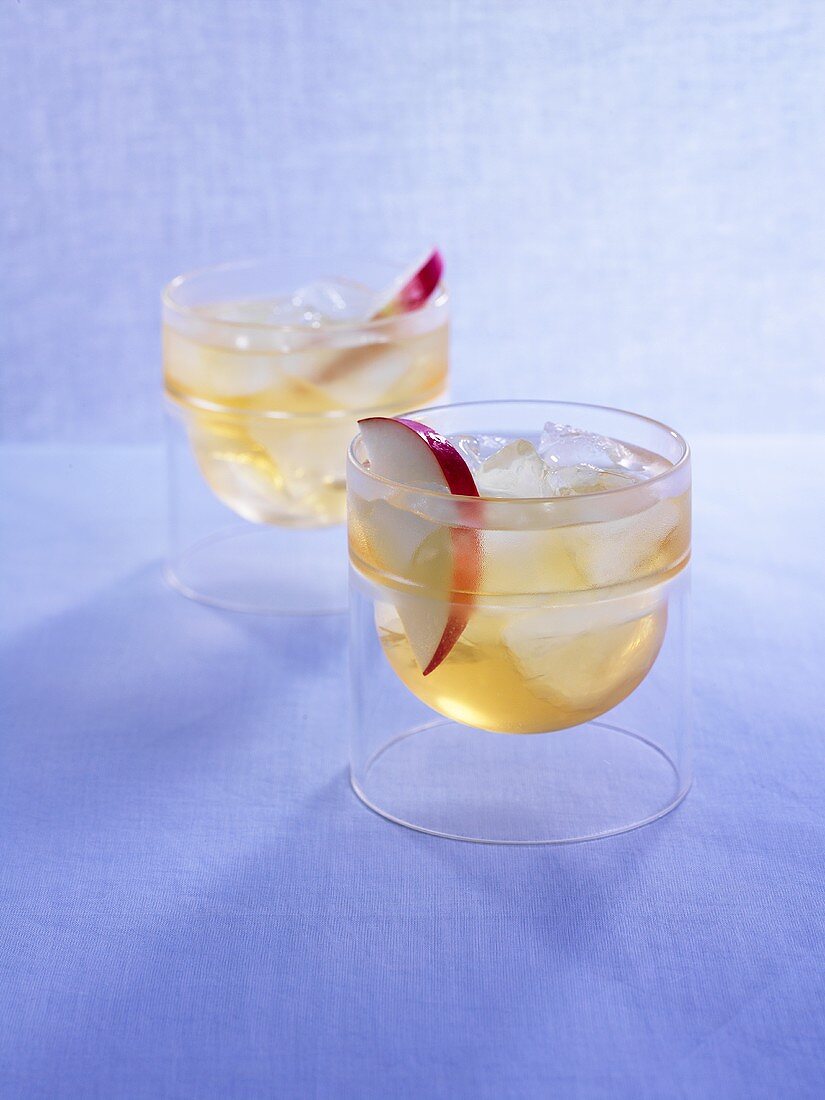 Two Drambuie cocktails with slices of apple and ice cubes