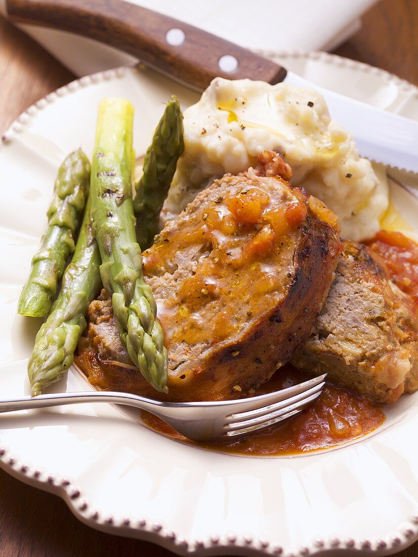 Bacon-wrapped meatloaf with tomato sauce, asparagus, mashed potato