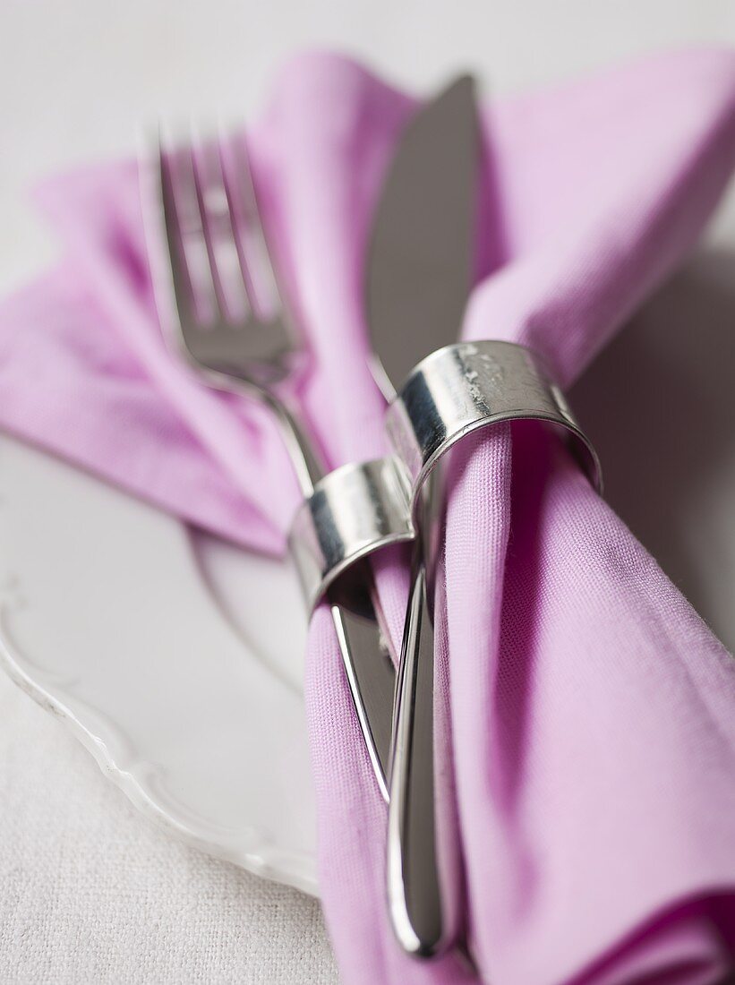 Fabric napkin with napkin ring and cutlery on plate