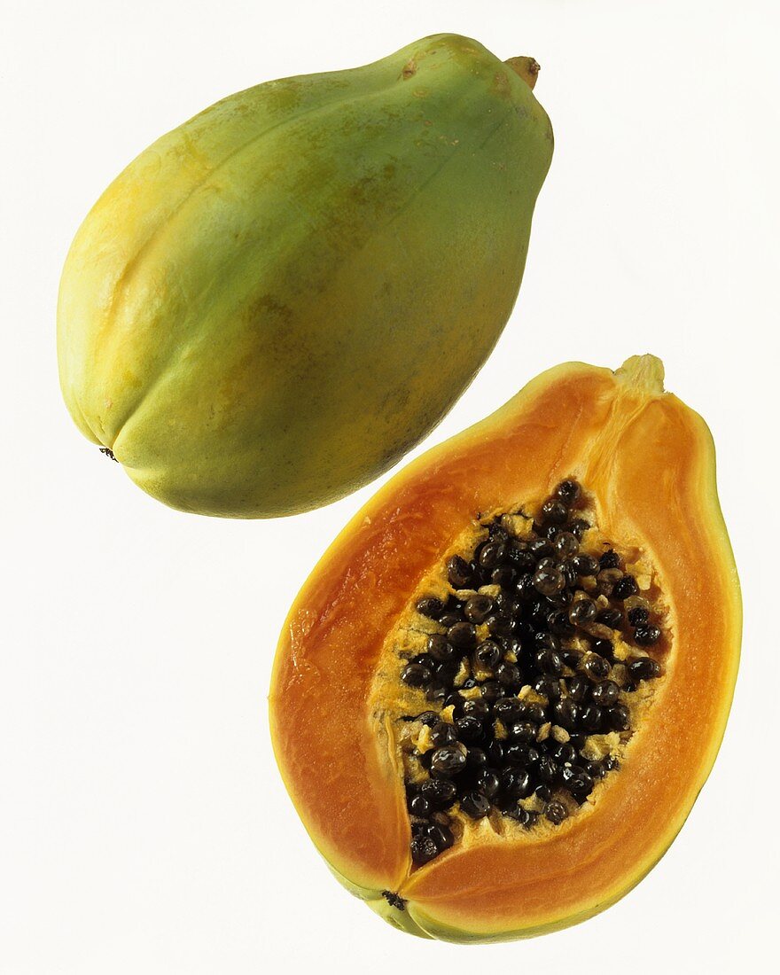 Ganze und halbe Papaya vor weißem Hintergrund