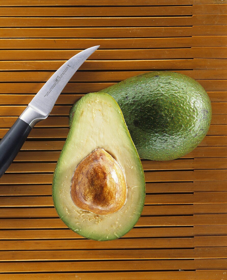 Ganze und halbierte Avocado mit Messer