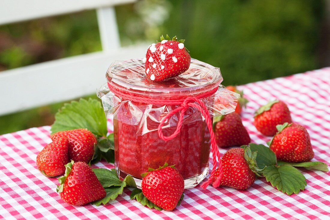 Cold stirred strawberry jam in a jar on a garden table