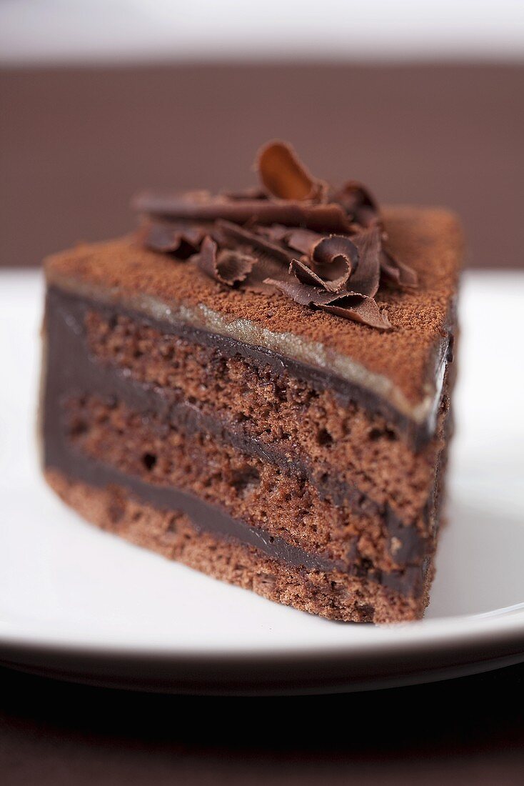 A slice of chocolate cake with chocolate flakes