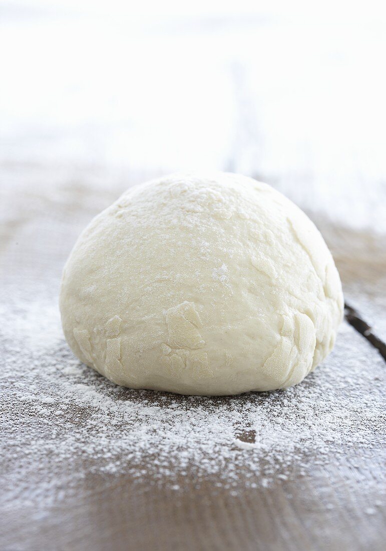 A ball of pizza dough on a wooden board