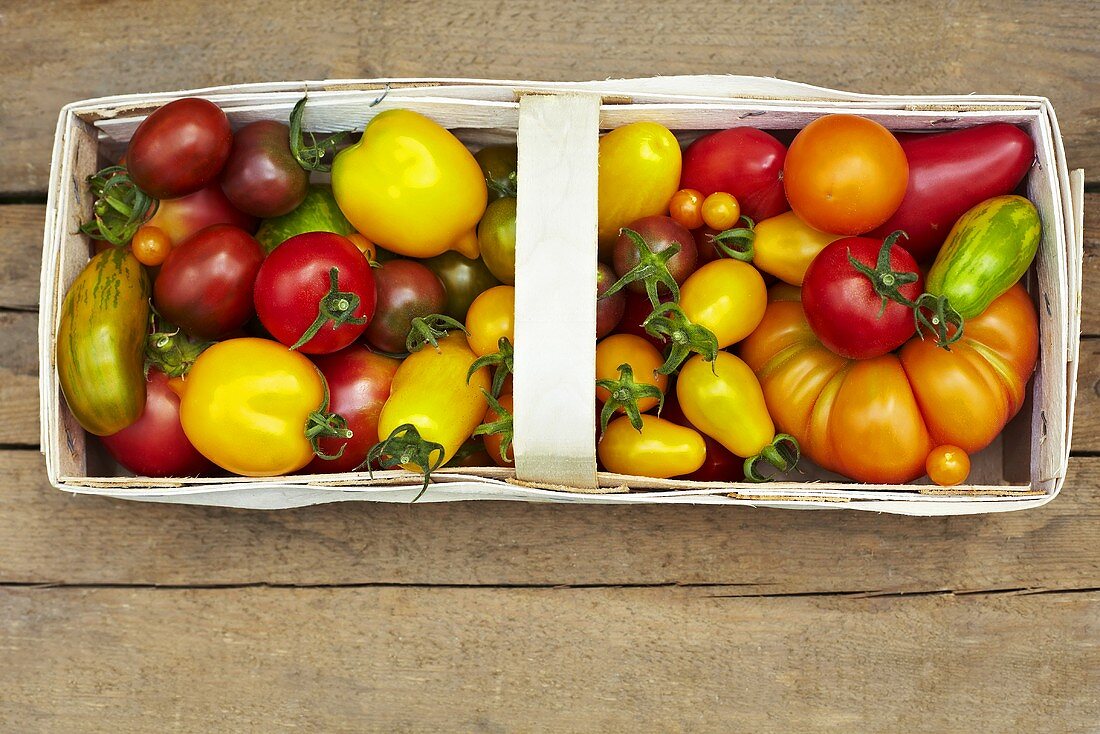 Various types of organic tomatoes in a wooden basket