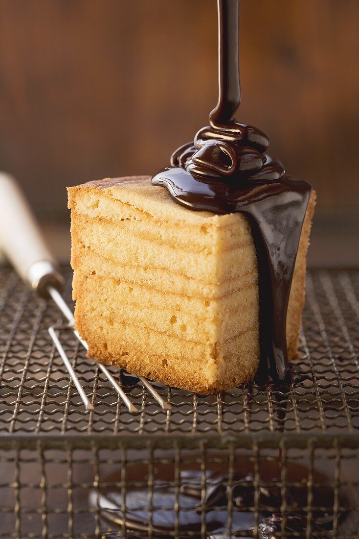 Baumkuchen (German layer cake) being prepared: covering the finished cake with chocolate glaze
