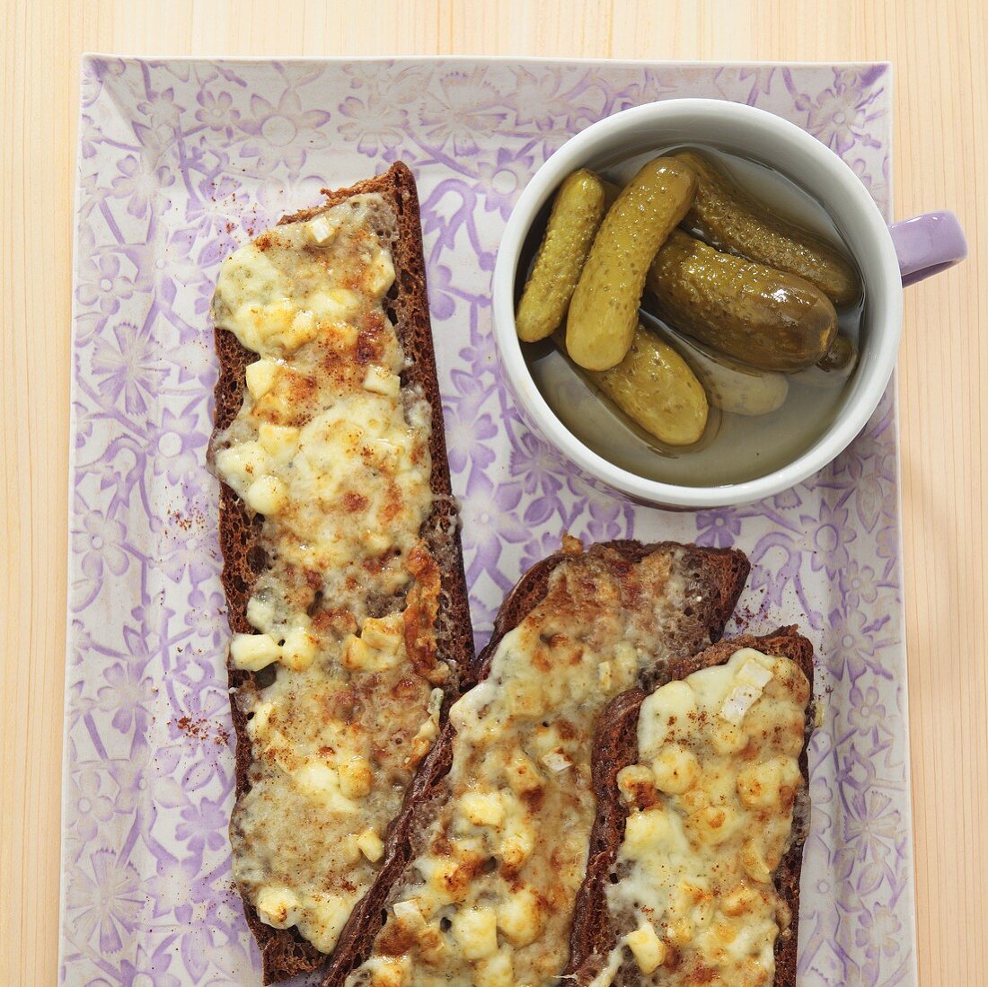 Toasted slices of bread with melted cheese and gherkins