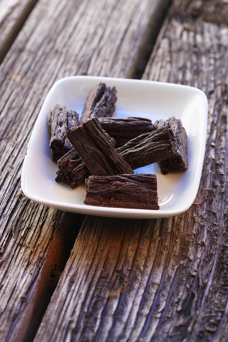 Flaked chocolate bars in a bowl on a wooden surface