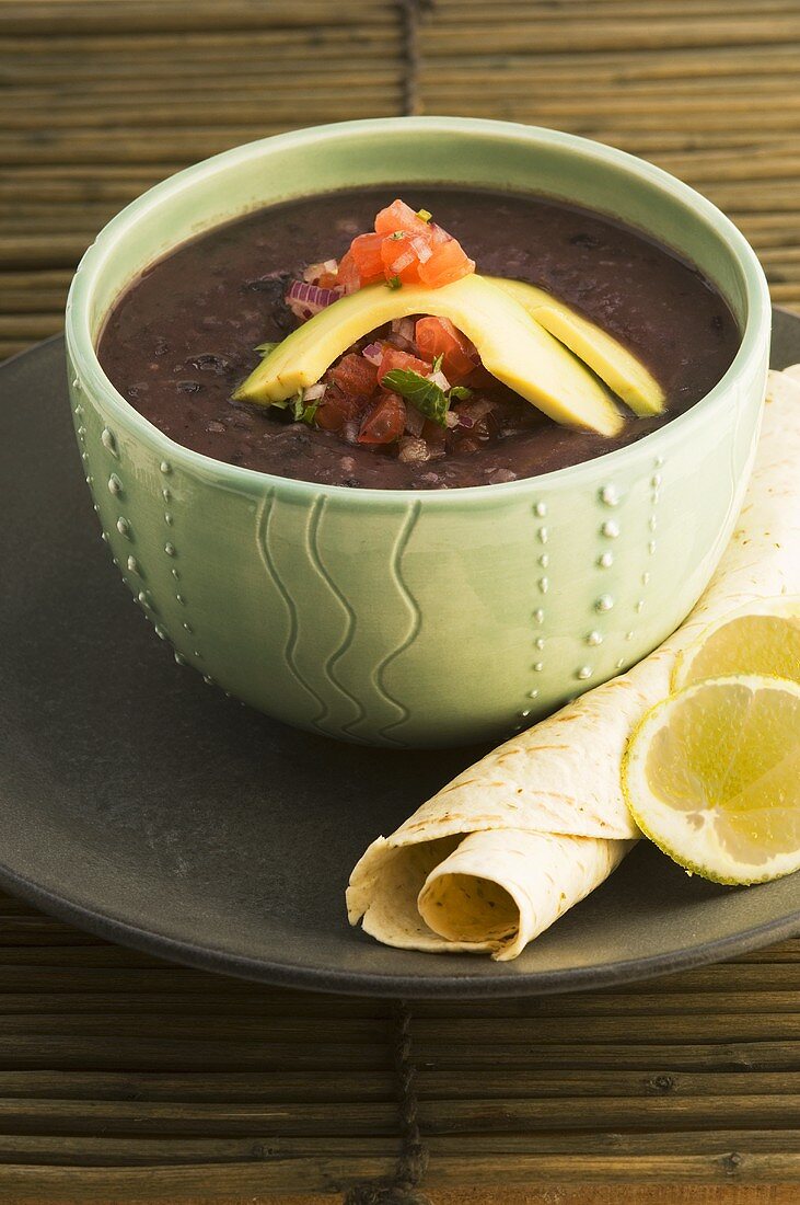 Suppe aus schwarzen Bohnen mit Avocado und Tomatensalsa; dazu eine Tortilla