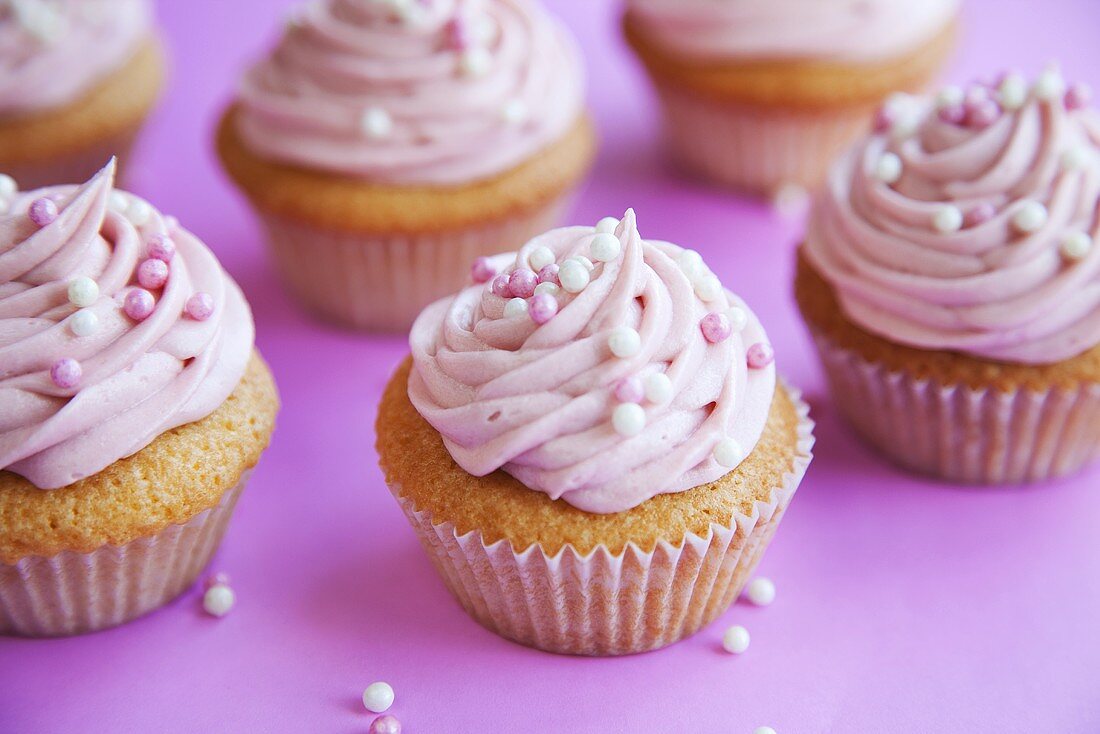 Mehrere Cupcakes mit rosa Creme und Zuckerperlen