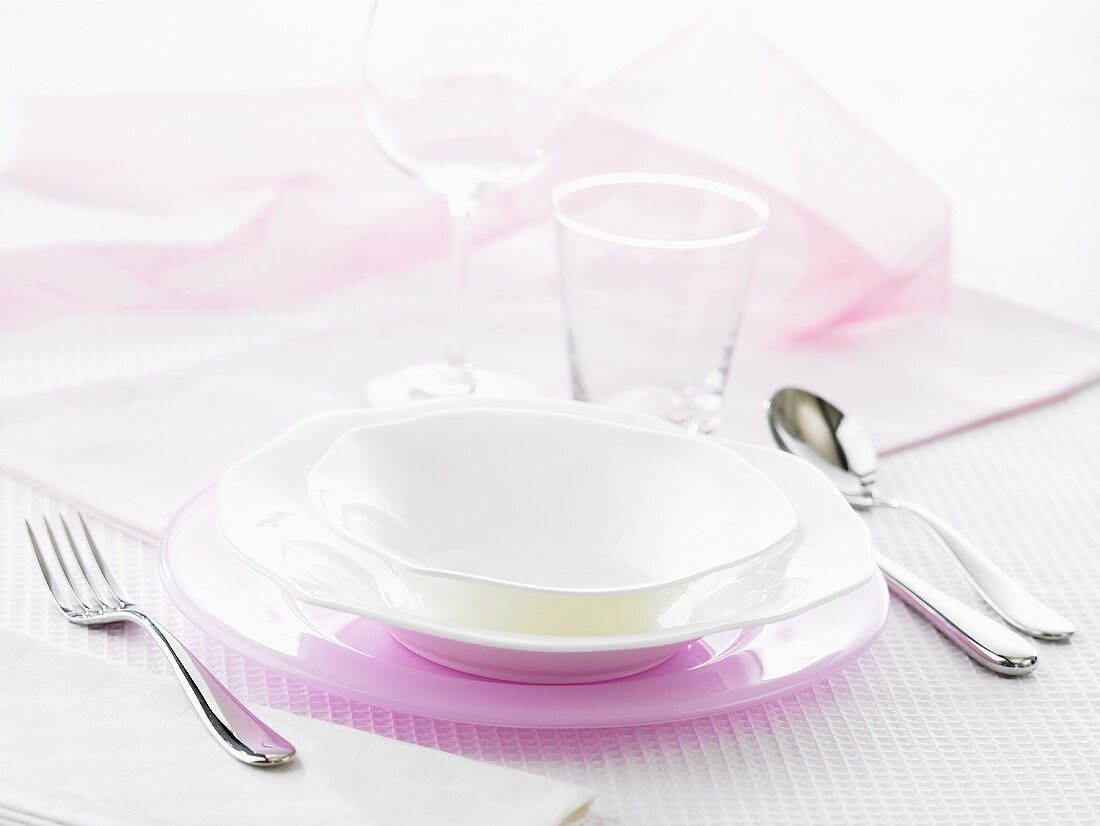 Gedeck mit rosa Platzteller und weissen Tellern