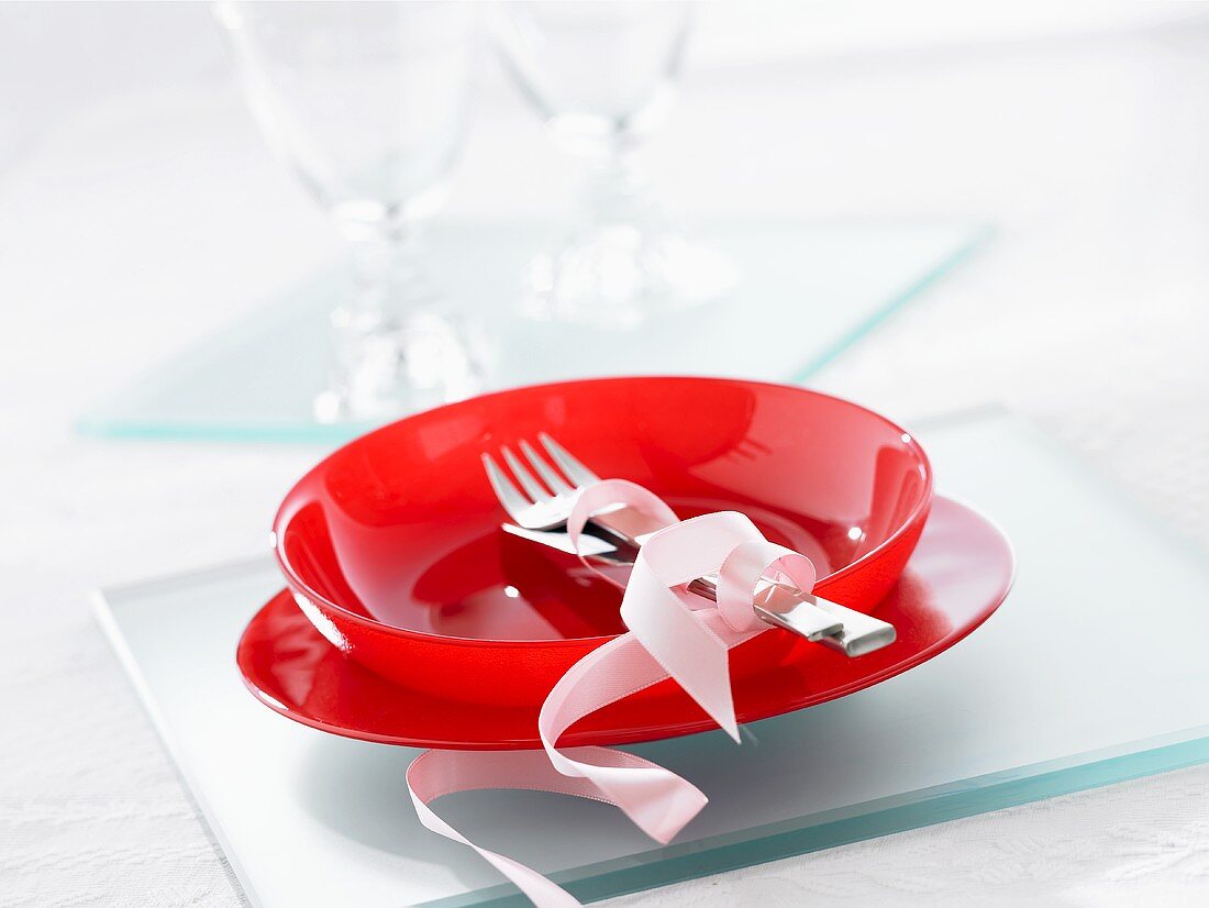 A place setting with red plates for dessert