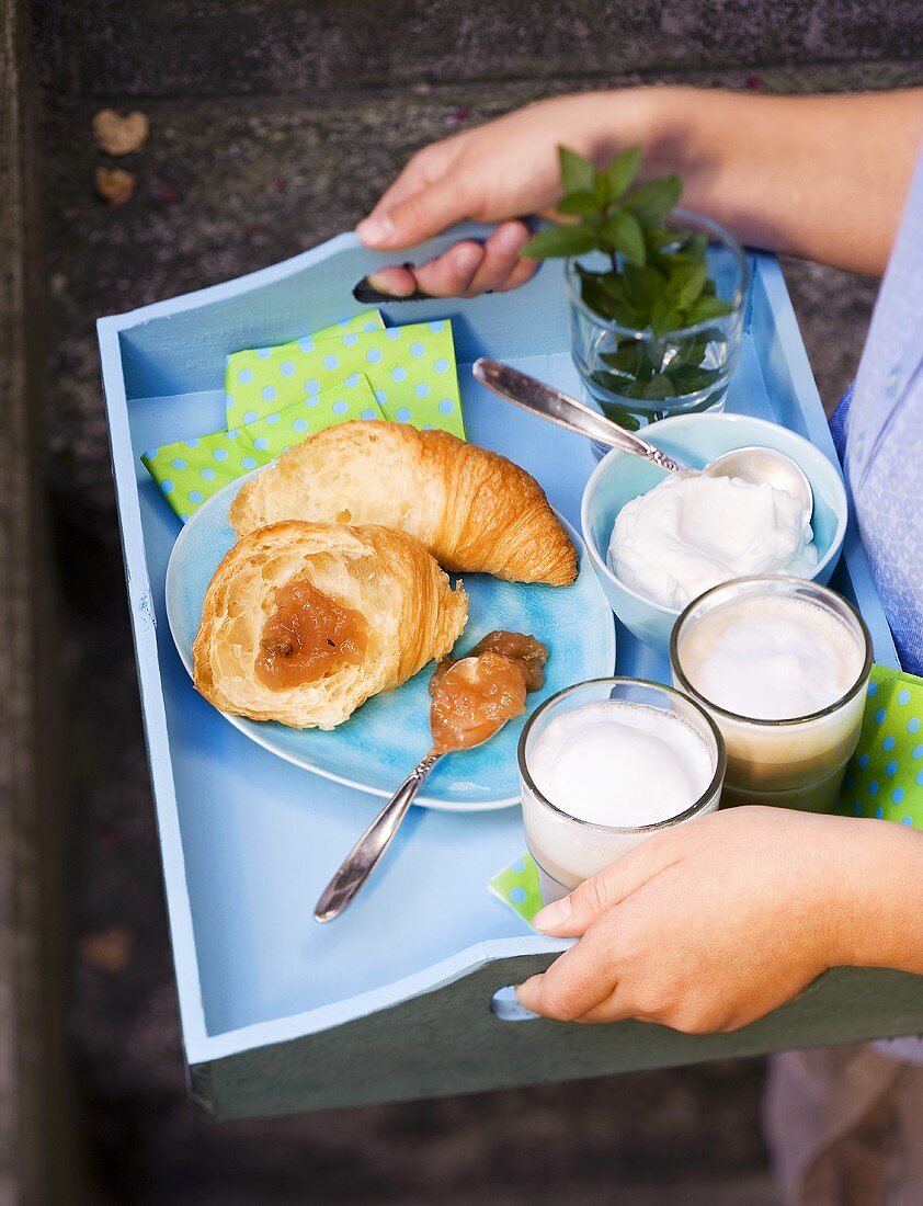A tray with a croissant, gooseberry jam and coffee