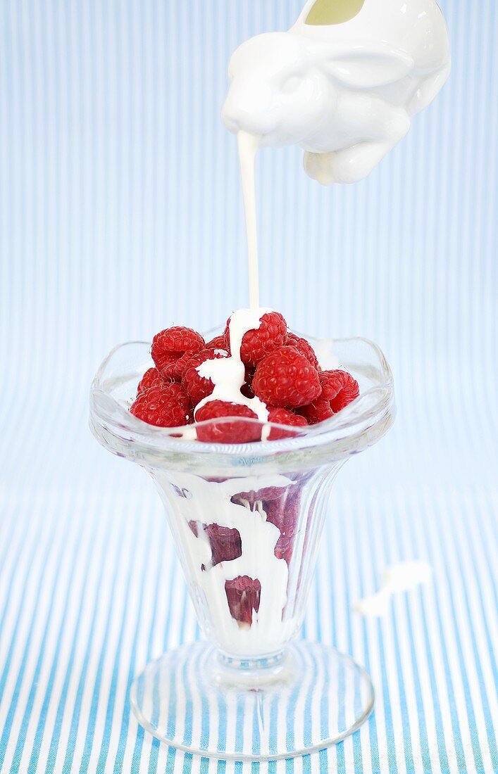 Cream being poured over raspberries