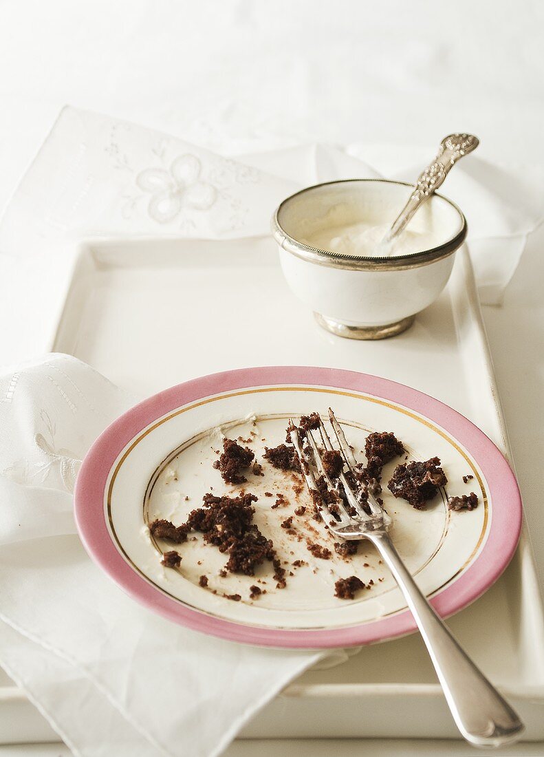 Chocolate cake crumbs on a plate with a bowl of cream