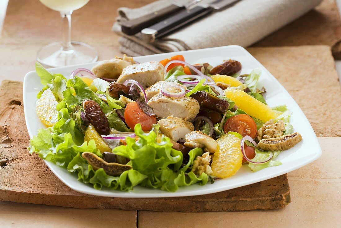 A winter salad with chicken, dried fruits and oranges