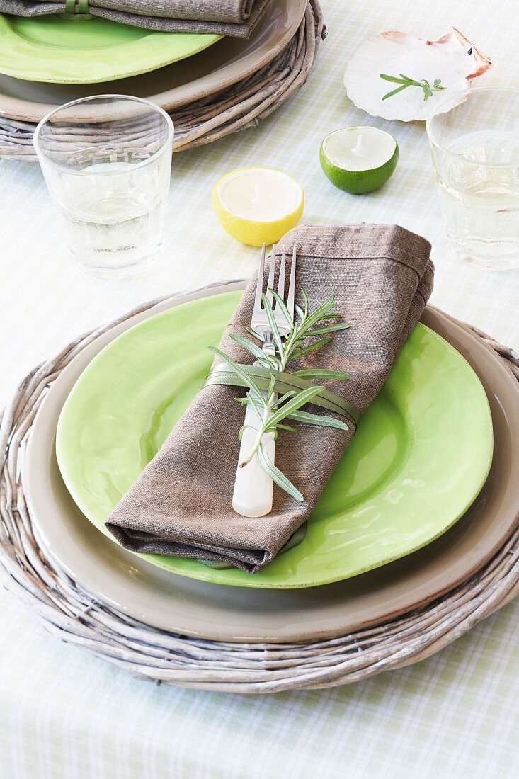 A place setting with a plate in a basket and a napkin decorated with rosemary