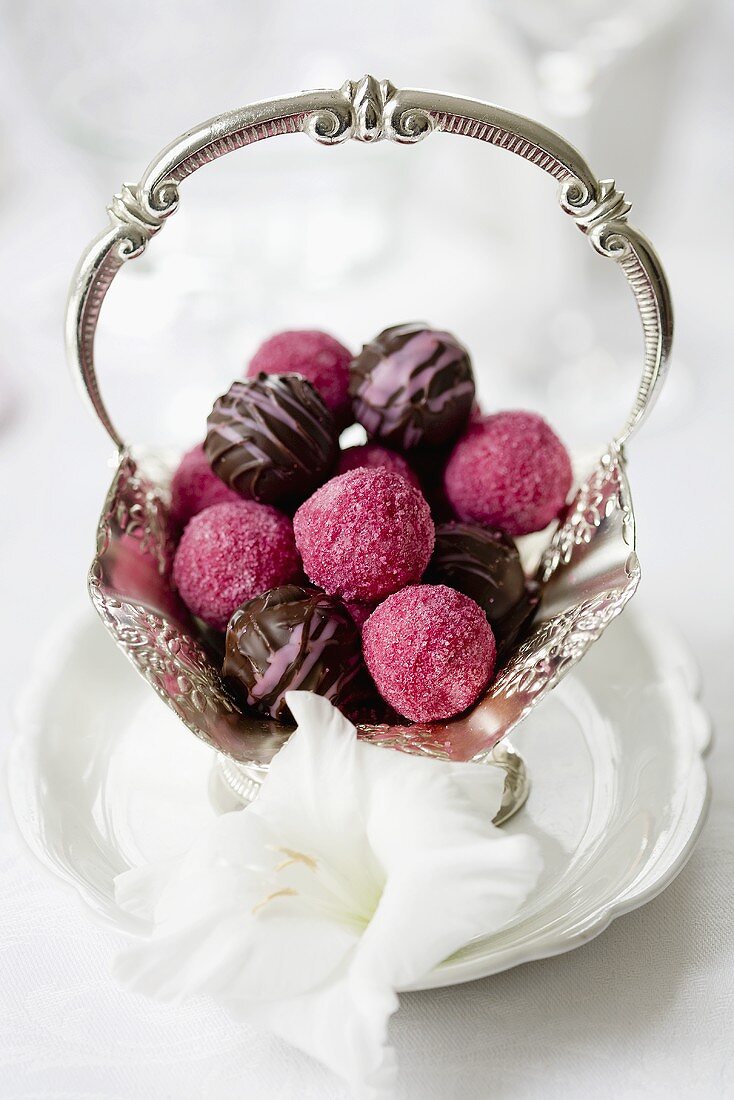 Various truffle pralines in a silver bowl decorated with flowers