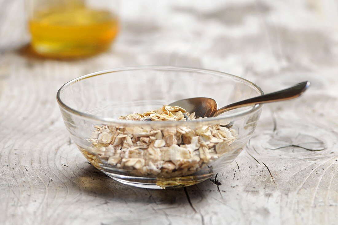 Muesli in a glass bowl with honey in the background